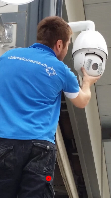 Telecamera di videosorveglianza dome montata su soffitto in legno con parete in intonaco bianco e dispositivo di rete sullo sfondo